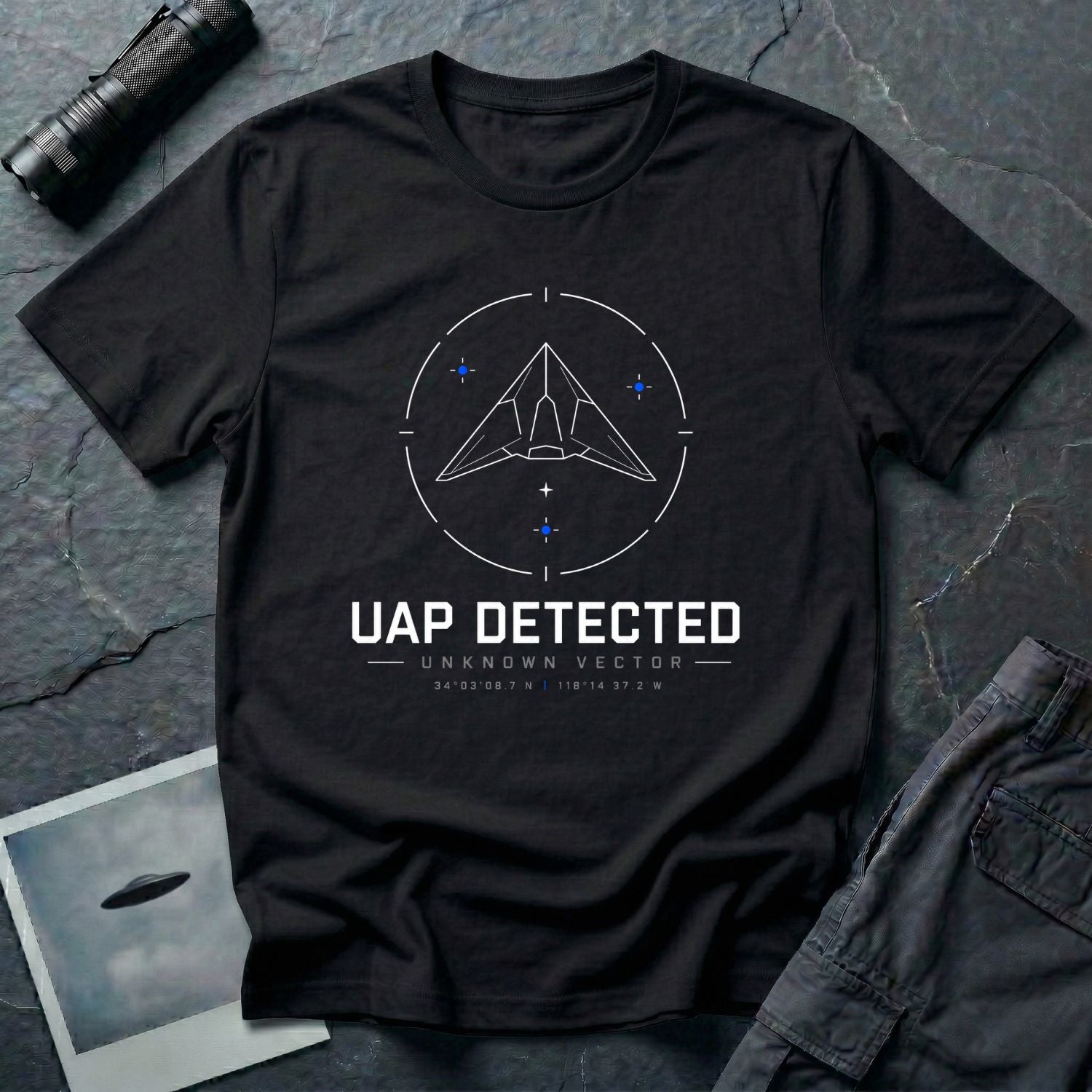 Black t-shirt with geometric angular UAP inside circular radar targeting reticle with UAP DETECTED UNKNOWN VECTOR text and GPS coordinates in white and blue linework