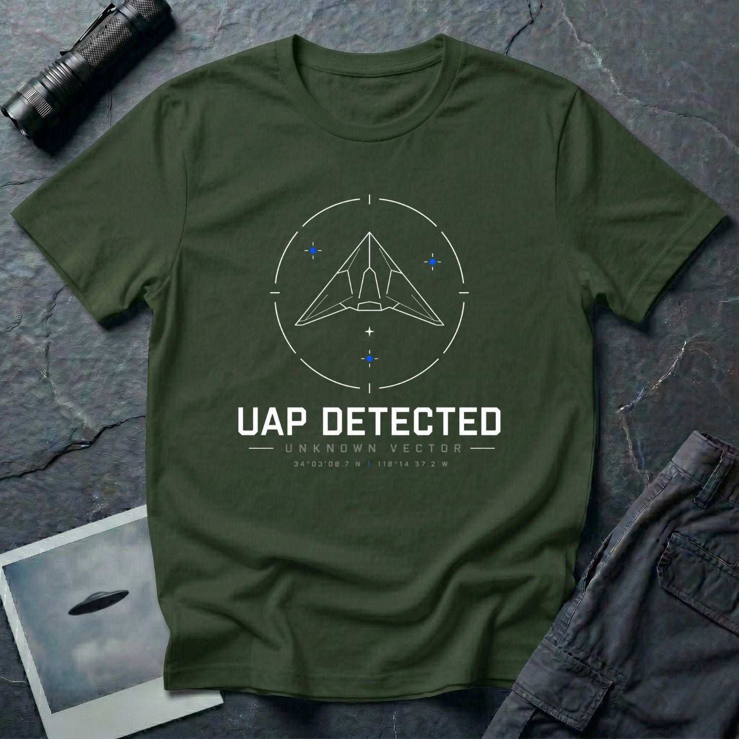Military green t-shirt with geometric angular UAP inside circular radar targeting reticle with UAP DETECTED UNKNOWN VECTOR text and GPS coordinates in white and blue linework