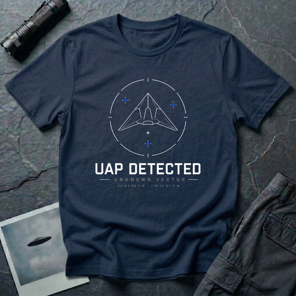 Navy blue t-shirt with geometric angular UAP inside circular radar targeting reticle with UAP DETECTED UNKNOWN VECTOR text and GPS coordinates in white and blue linework