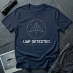 Navy blue t-shirt with geometric angular UAP inside circular radar targeting reticle with UAP DETECTED UNKNOWN VECTOR text and GPS coordinates in white and blue linework