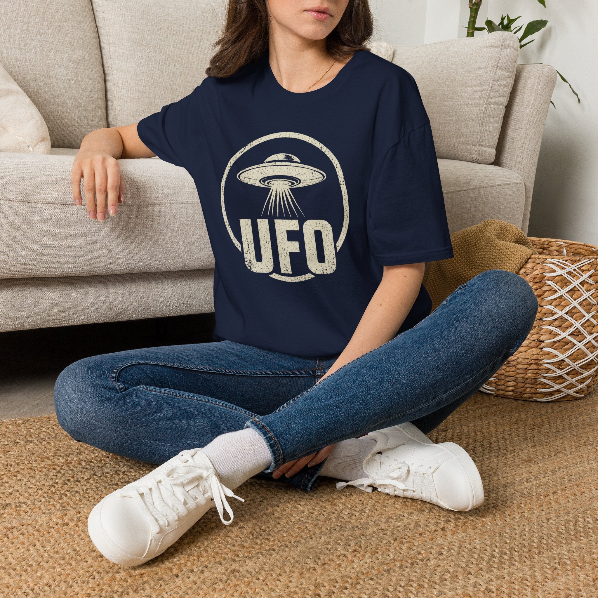 Person wearing blue retro UFO t-shirt with a distressed circle containing a flying saucer with tractor beam and bold block letters spelling UFO in white