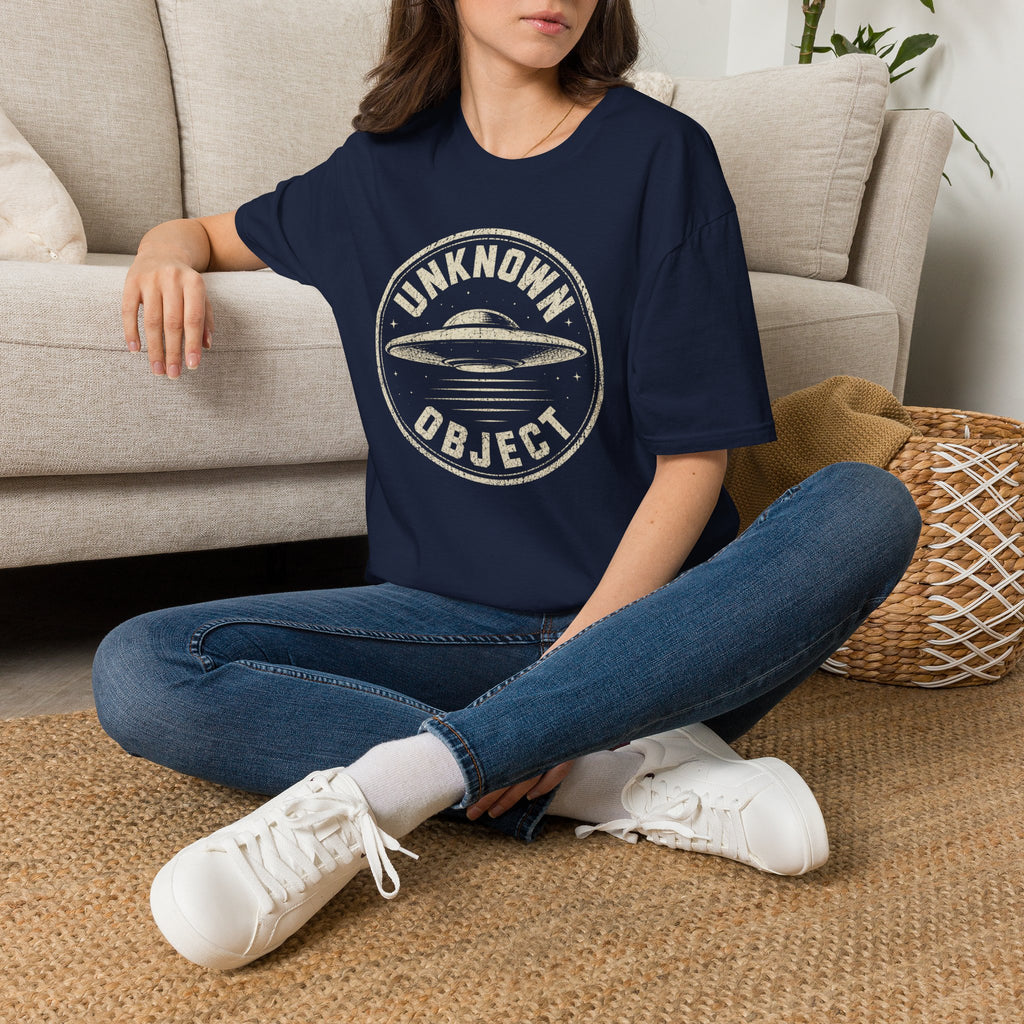 Person wearing navy blue retro UFO t-shirt with a distressed circular badge showing a flying saucer with speed lines and the words UNKNOWN OBJECT in white