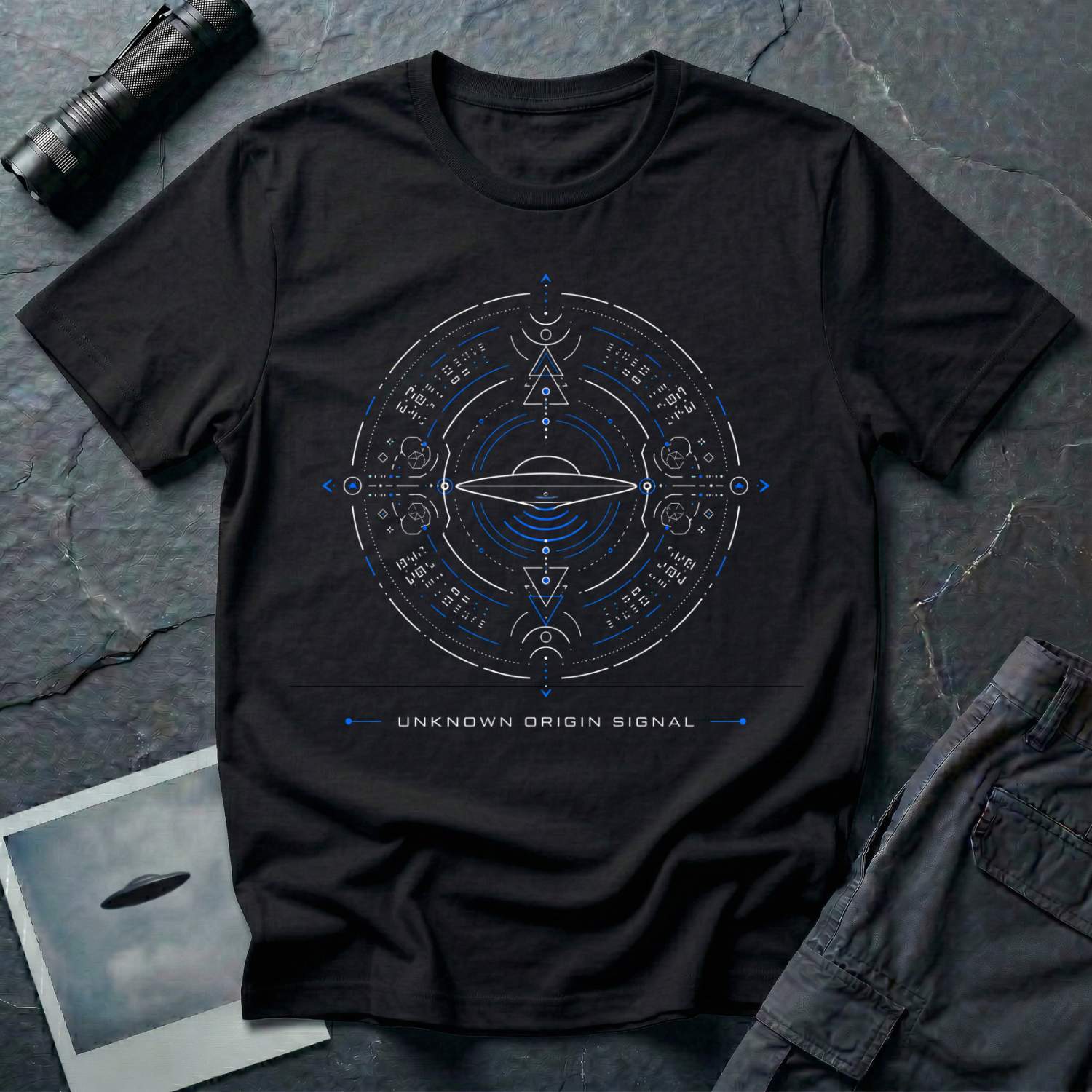 Black t-shirt with circular SETI-style schematic featuring encoded alien script outer ring compass points and central saucer in blue and white linework with UNKNOWN ORIGIN SIGNAL caption