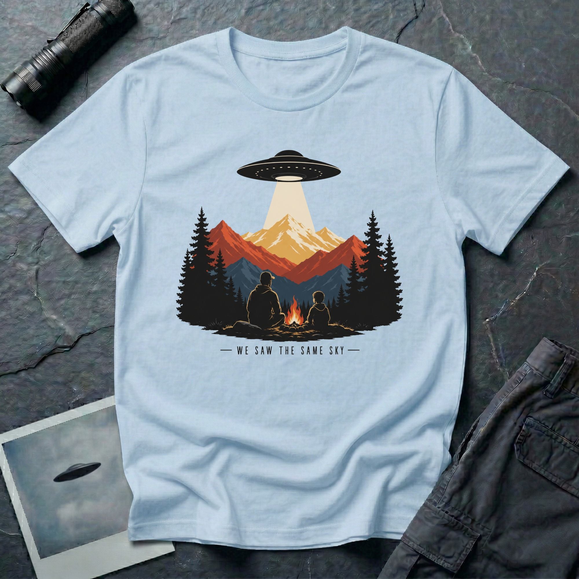 We Saw the Same Sky UFO t-shirt with father and child at campfire watching saucer over mountains, light blue