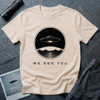 Natural t-shirt with a UFO hovering over mountains and a reflective lake inside a circular night scene badge with the words WE SEE YOU in black and gold